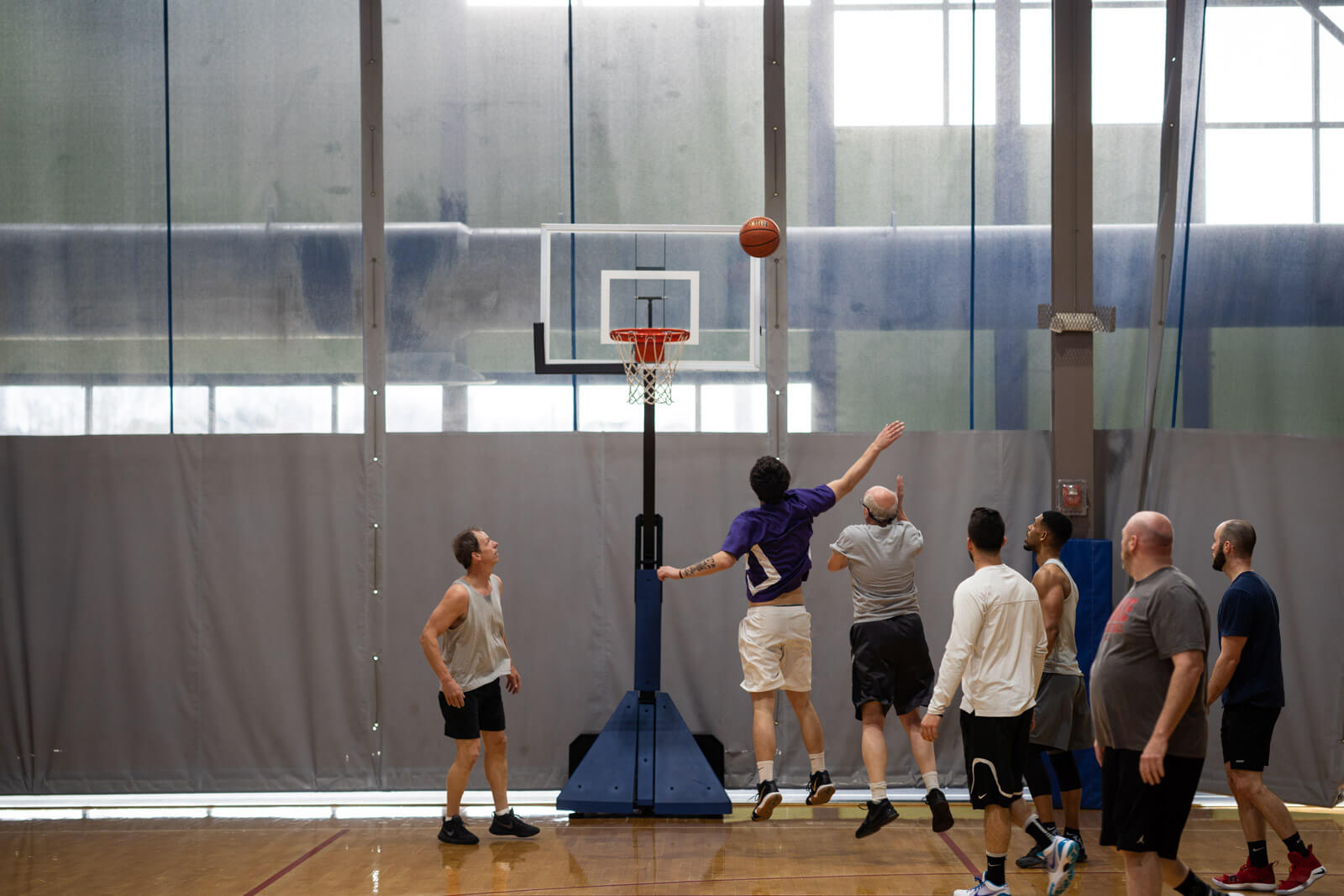Men playing basketball on an indoor court.