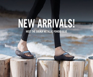 Person standing on wooden posts wearing OOFOS recovery sandals